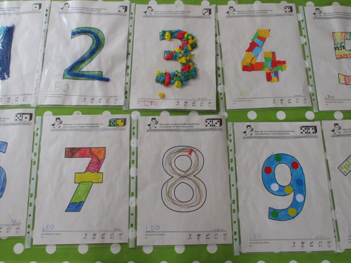 Foto von selbstgebastelten bunt ausgemalenen Zahlen auf DIN A4 Papier. 