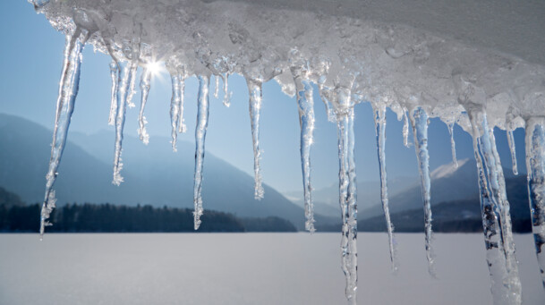 unbekannt, Sylvensteinspeicher Im Vordergrund sind Eiszapfen die in das Bild hinein ragen und im Hintergrund sieht mann den Sylvensteinspeicher im Winter